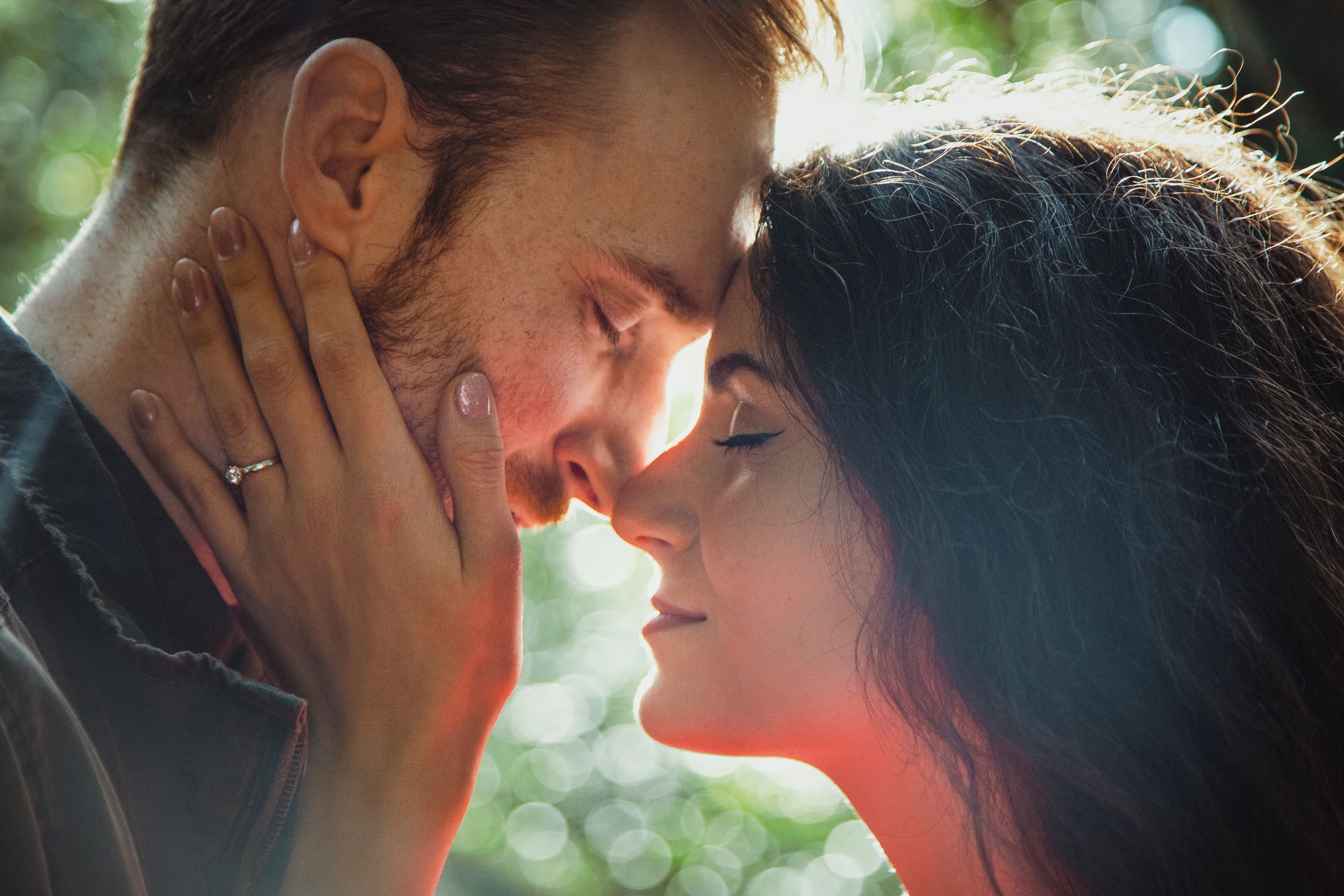 A close-up romantic portrait in dappled forest light with intimate expressions.