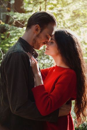 An intimate forest photoshoot featuring a couple in casual attire with natural lighting.