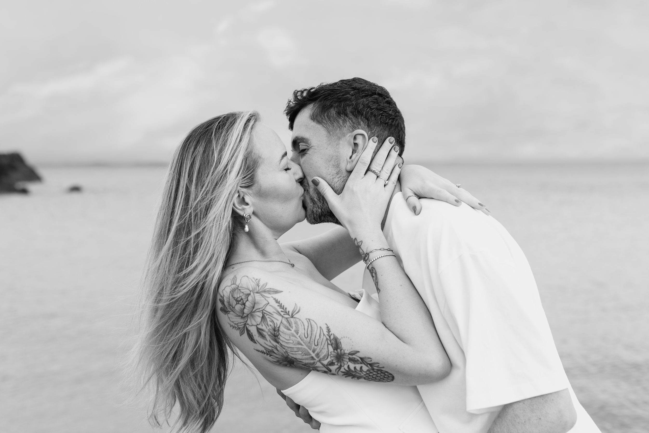 Romantic black and white beach portrait of a couple sharing a tender moment.