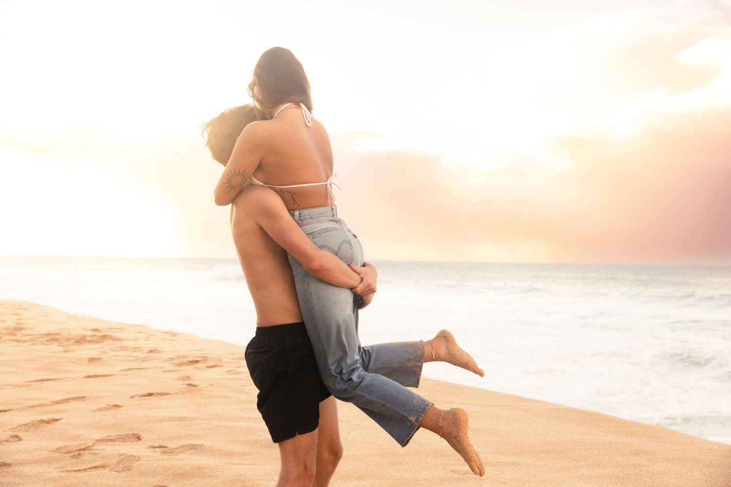 A tender embrace on a beach during golden hour sunset.