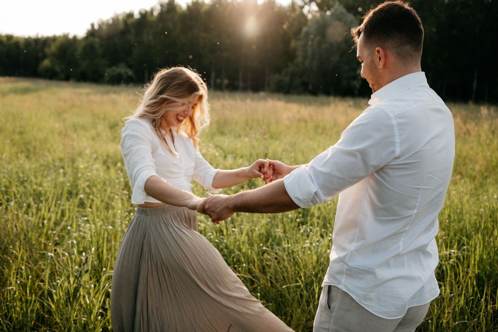 A romantic couple dancing and twirling in a golden summer field at dusk.