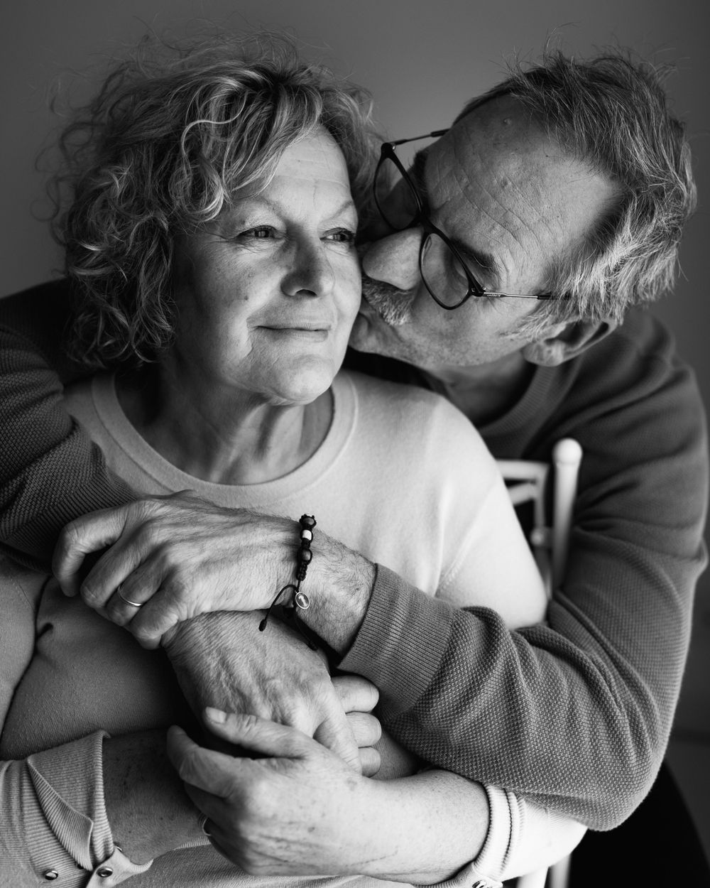 Black and white portrait capturing a gentle moment between two people in a close embrace.