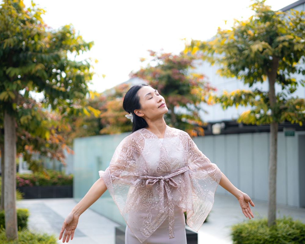 Dancing movement in pink lace dress captured against garden landscape.