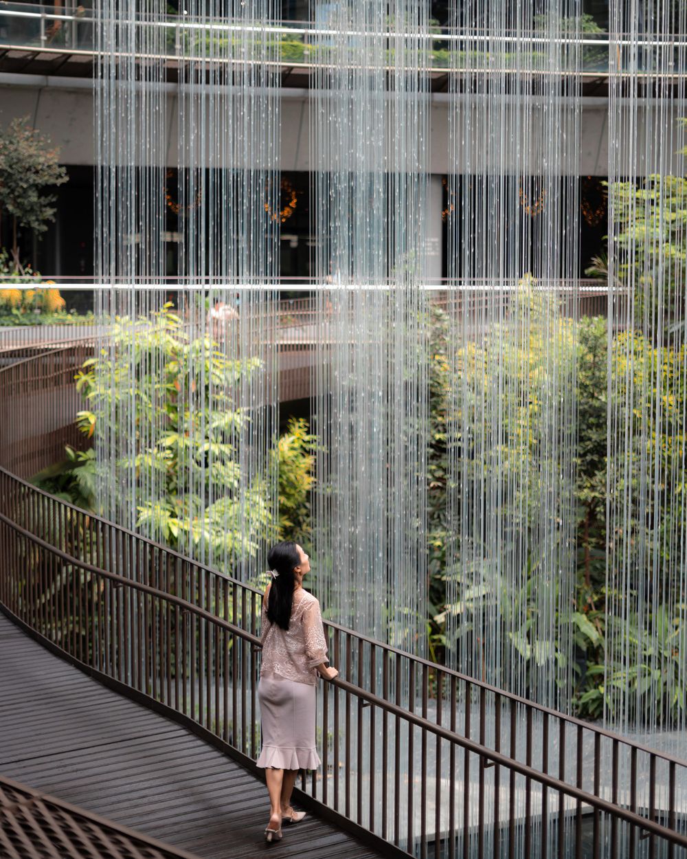 Dramatic architectural scene with water features and walkway surrounded by tropical plants.