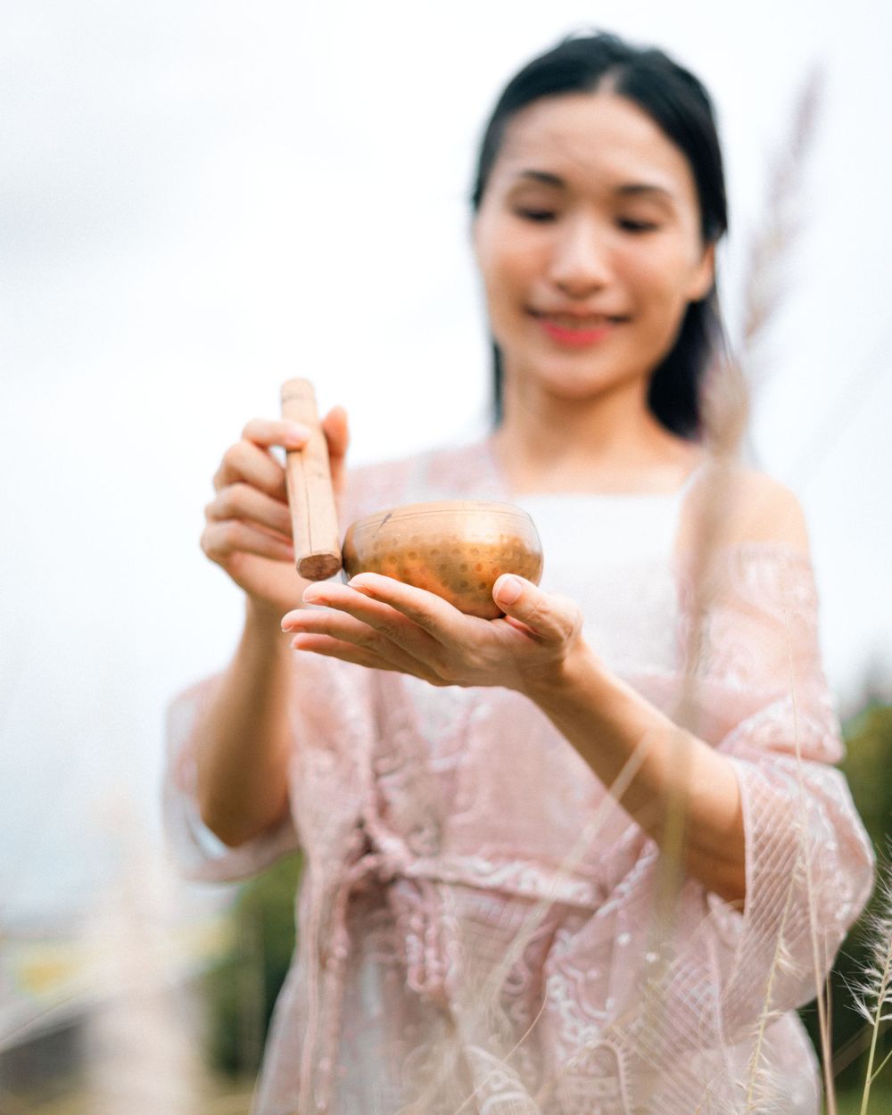 Woman in pink lace dress holding something delicate outdoors in soft focus.