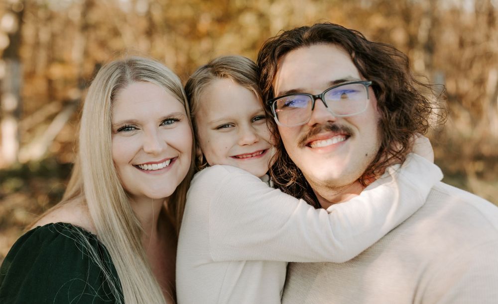 Family members embracing and laughing during outdoor portrait session.