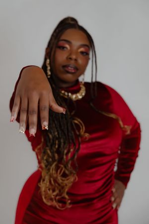 Close-up fashion portrait showing red dress, statement jewelry, and dramatic makeup.