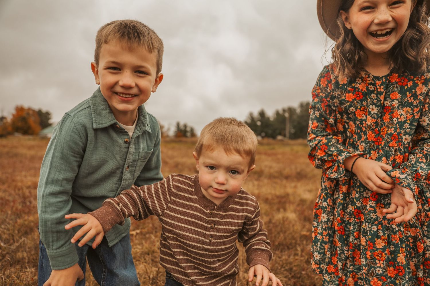 Three sibling laughing together in a candid moment in Maine