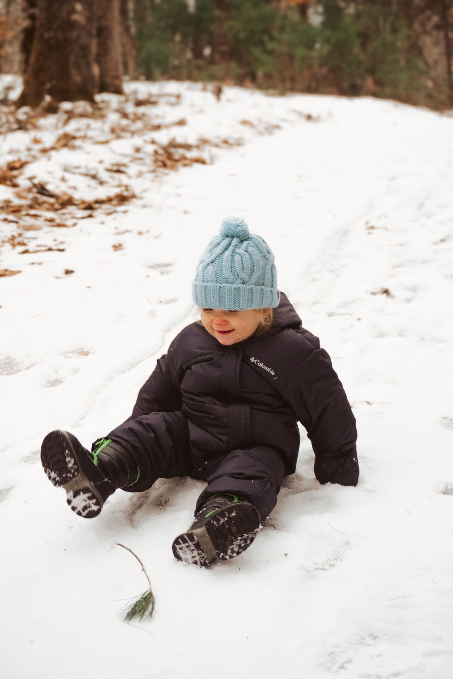 Toddler sitting in the snow in Maine