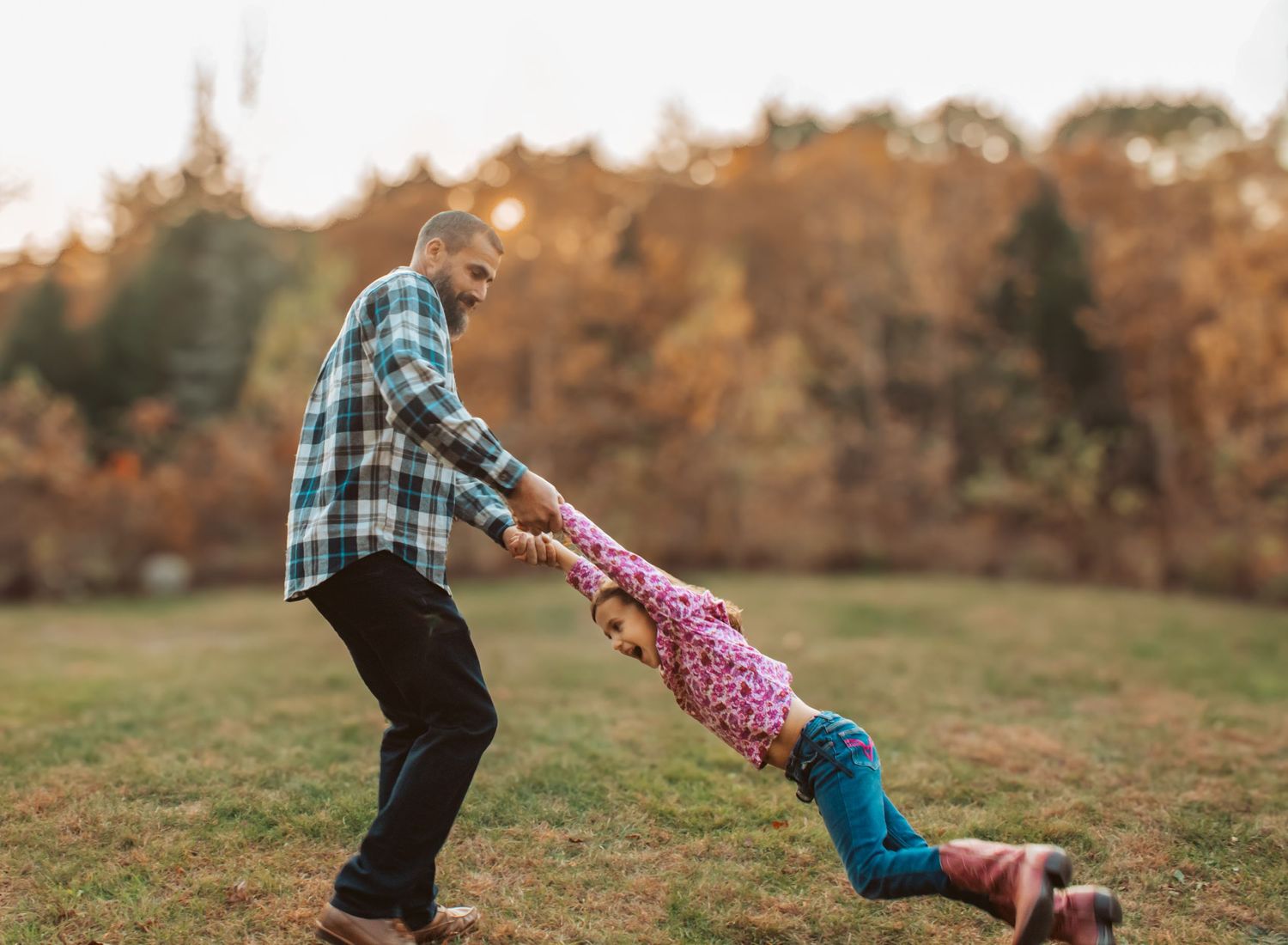 Father and Daughter playing together, spinning around the backyard in Maine