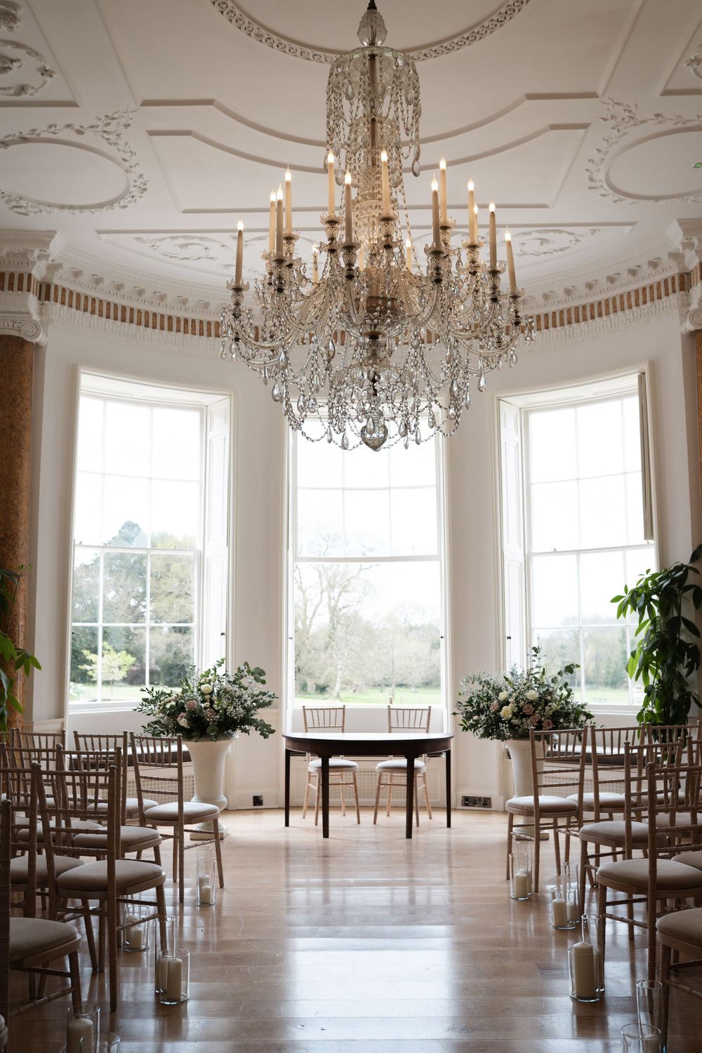 Elegant ballroom with crystal chandeliers, ornate ceiling details, and large windows.