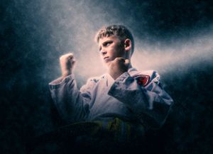 A figure stands in atmospheric smoke wearing a white martial arts uniform with dramatic lighting creating a moody effect.