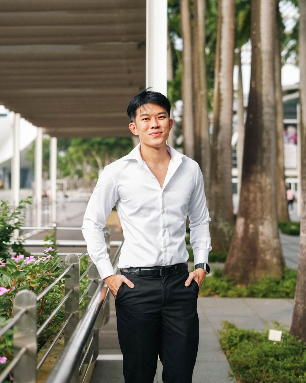 Casual business portrait with white shirt and black pants along outdoor walkway with trees.