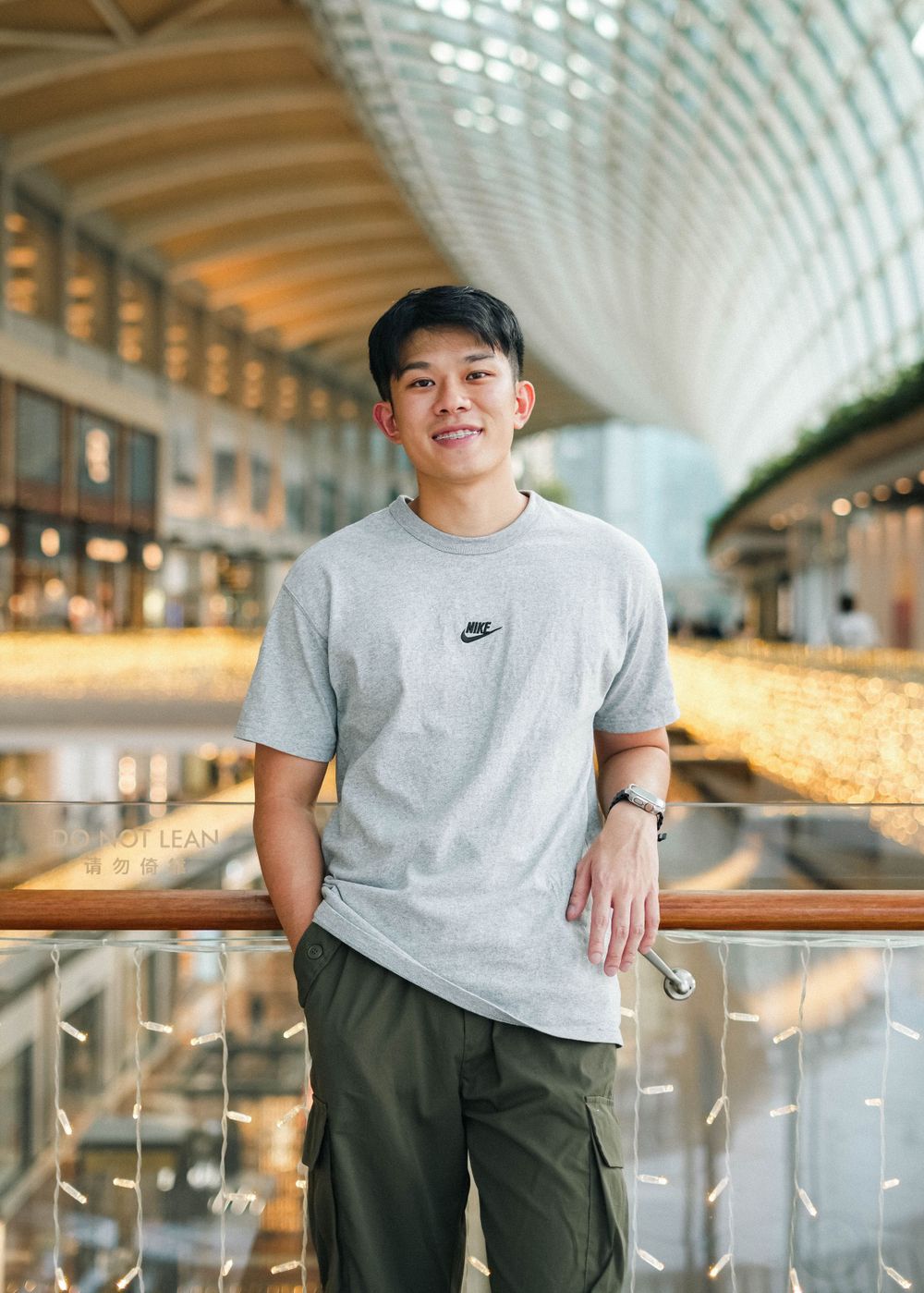Casual portrait in grey Nike t-shirt against modern interior with curved ceiling.