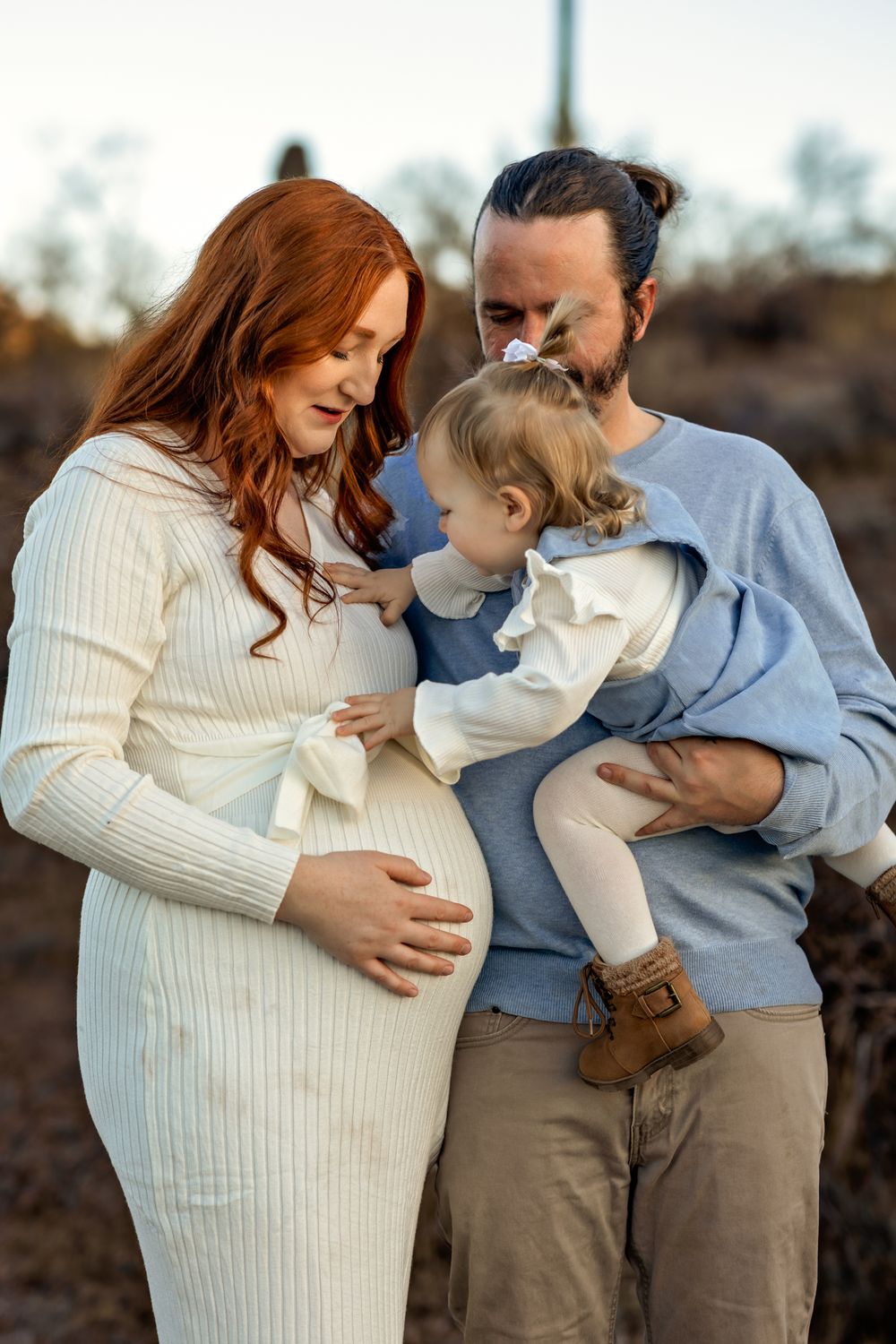Maternity family photo with expecting mother in white sweater dress and toddler.