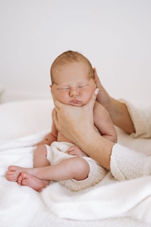 A series of peaceful baby details including feet, toes, and hands wrapped in soft white blankets against light backgrounds.