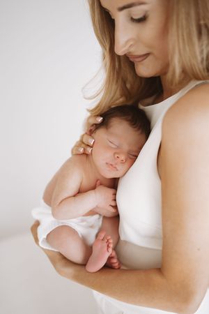 A tender moment captured in a series of intimate black and white photographs showing a mother cradling her sleeping newborn.