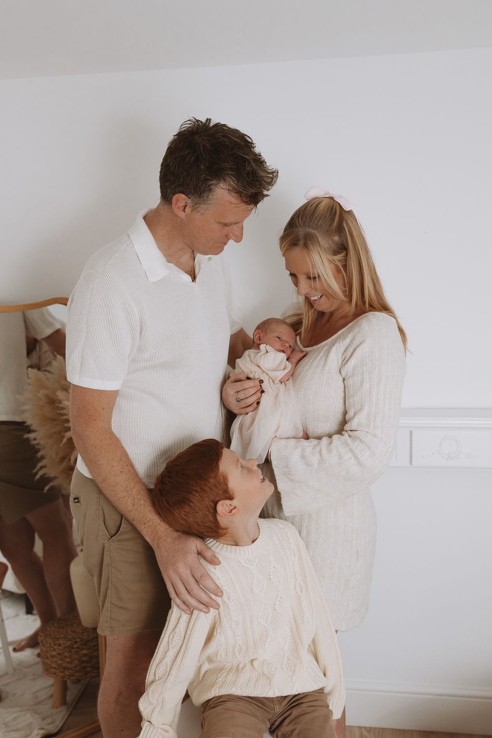 Family of three sharing tender moments together in a minimalist white room setting.