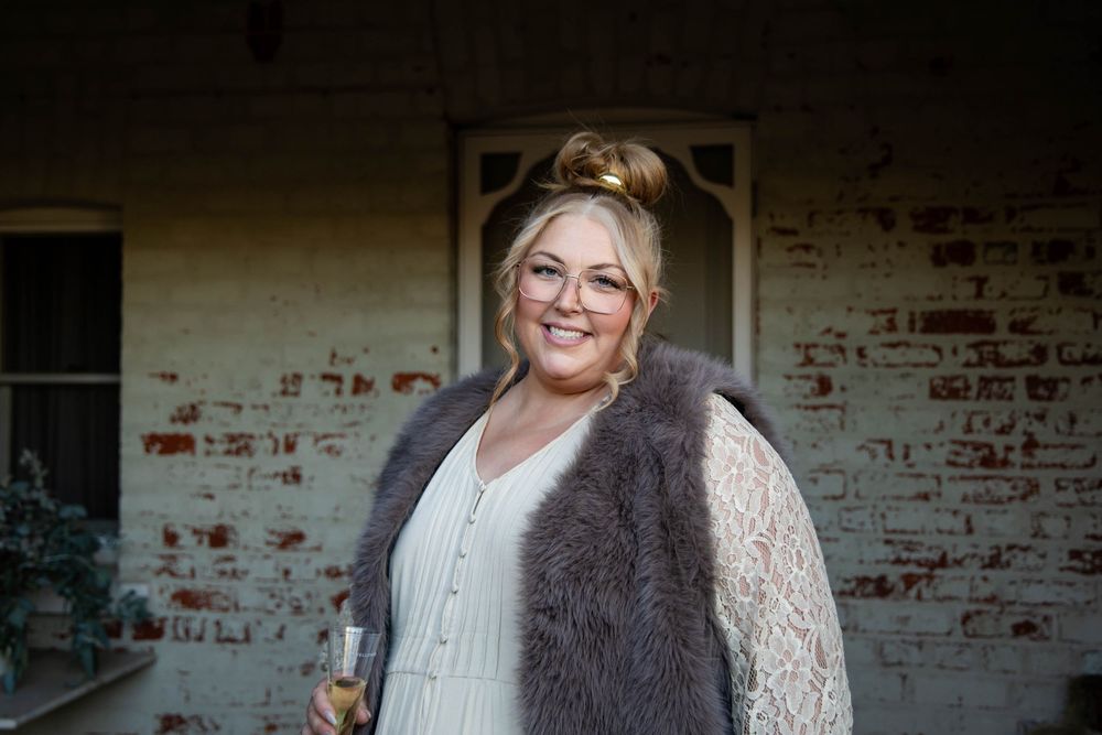 Group poses and smiles in rustic brick interior setting wearing white tops and dark furs.