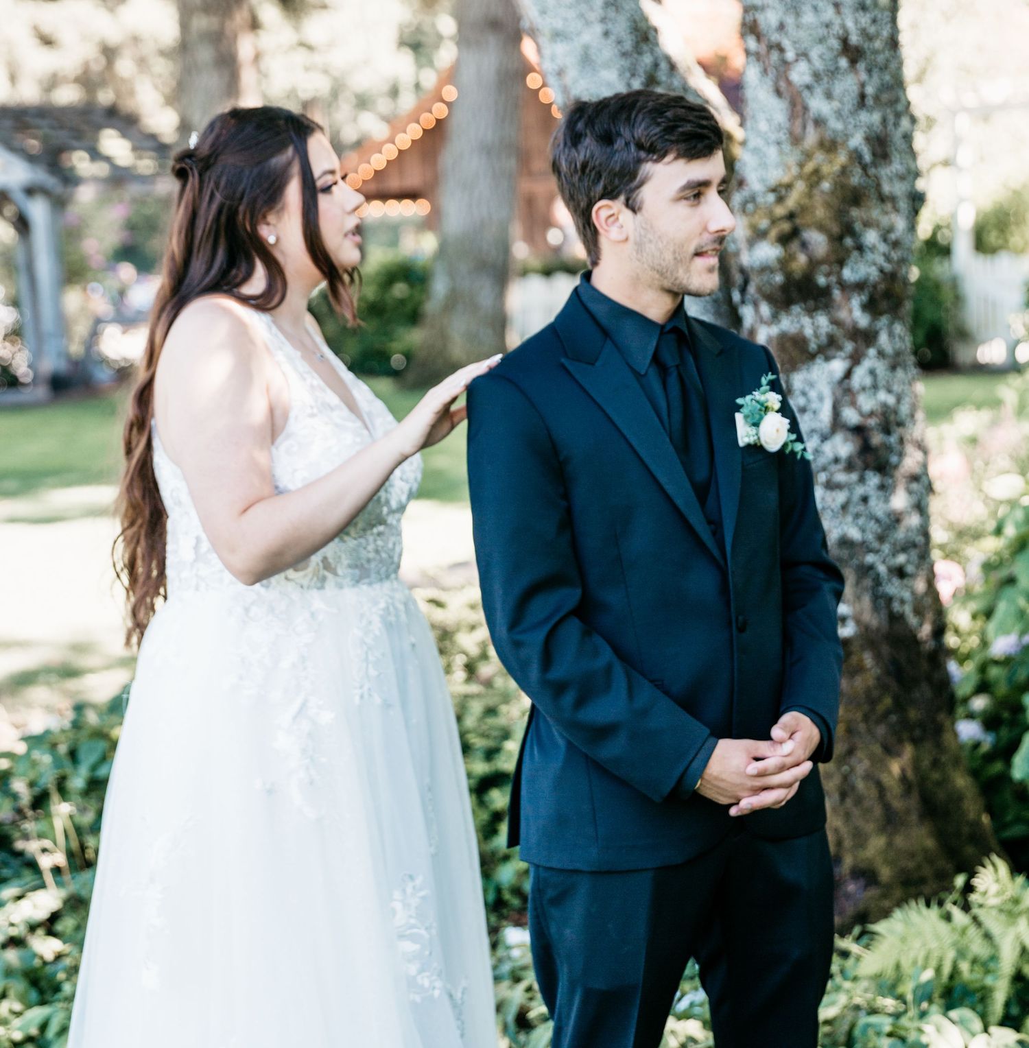 A couple shares a moment during their outdoor wedding ceremony, with the bride in white and groom in navy.
