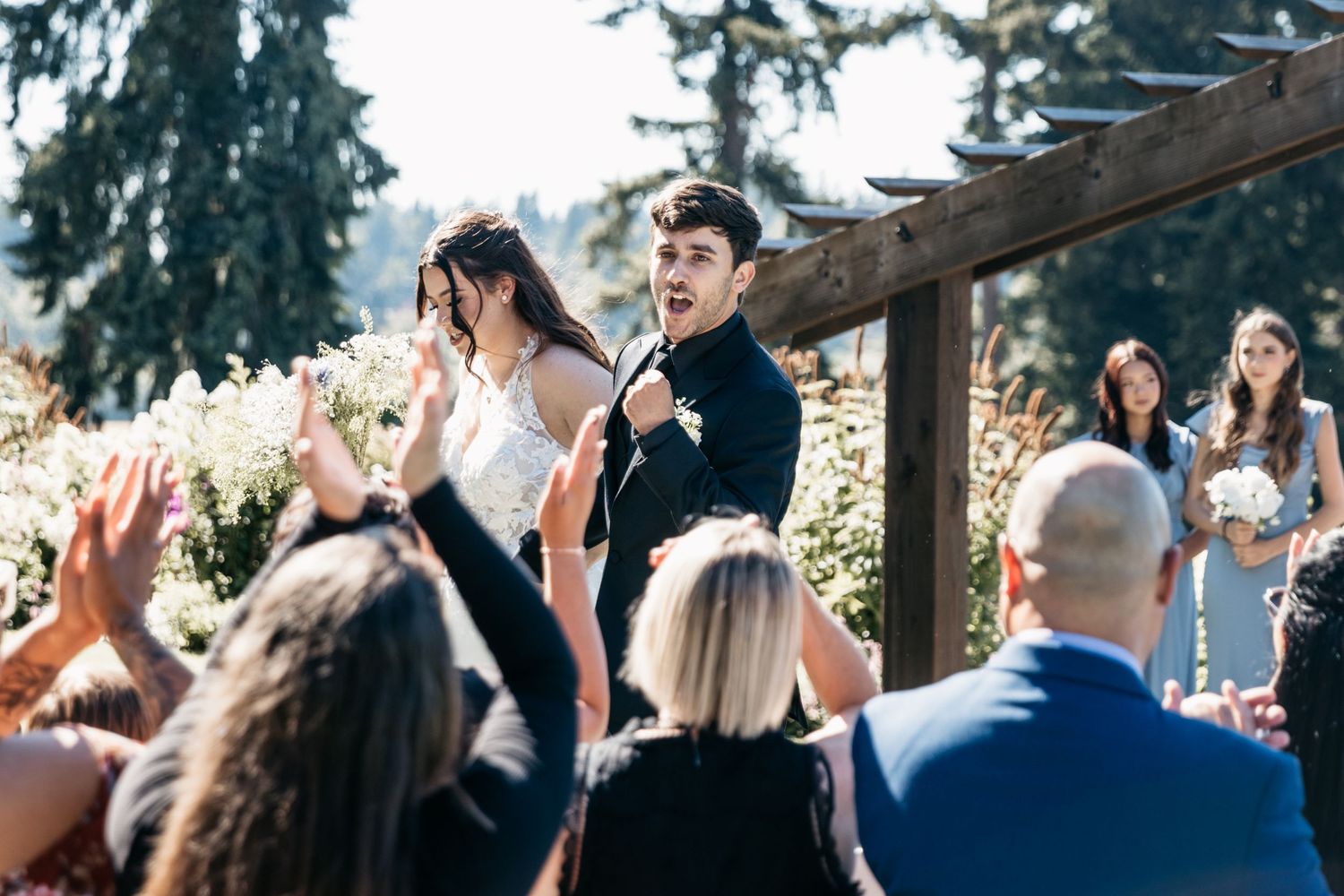 Wedding celebration on an elevated outdoor deck with guests cheering during the ceremony.