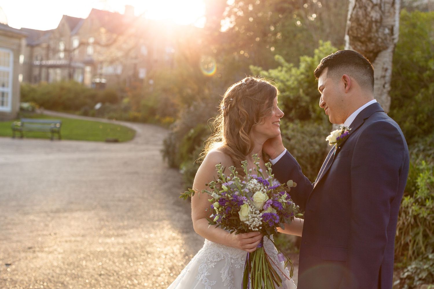 A tender sunset moment between newlyweds with soft golden light and fresh flowers.