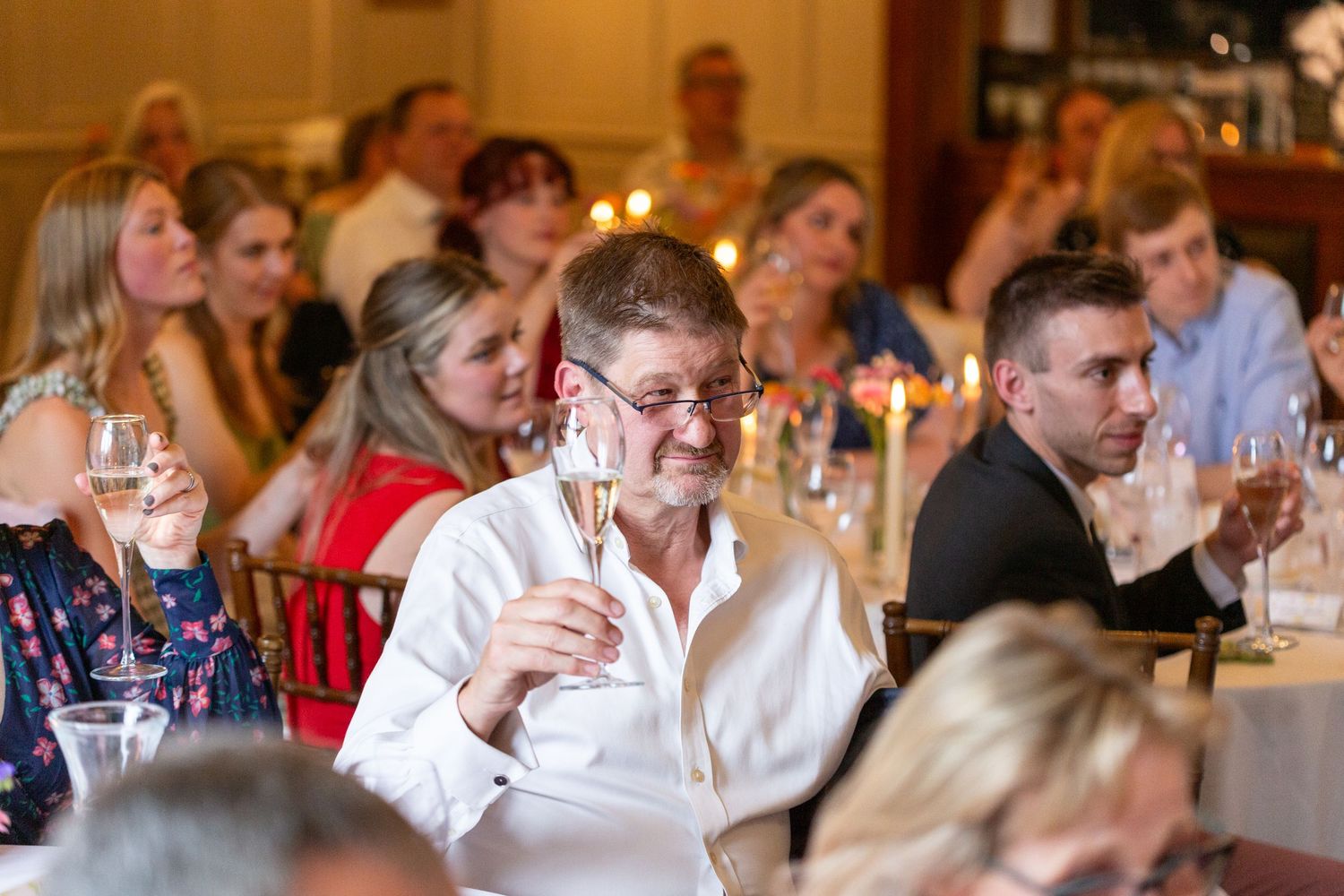 People seated at a formal dinner event in a restaurant setting with warm lighting and elegant table settings.