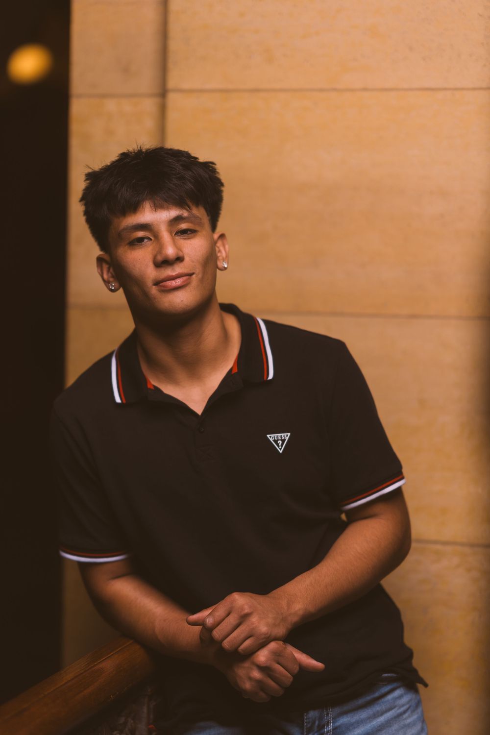 Casual portrait against wooden wall in black polo shirt.