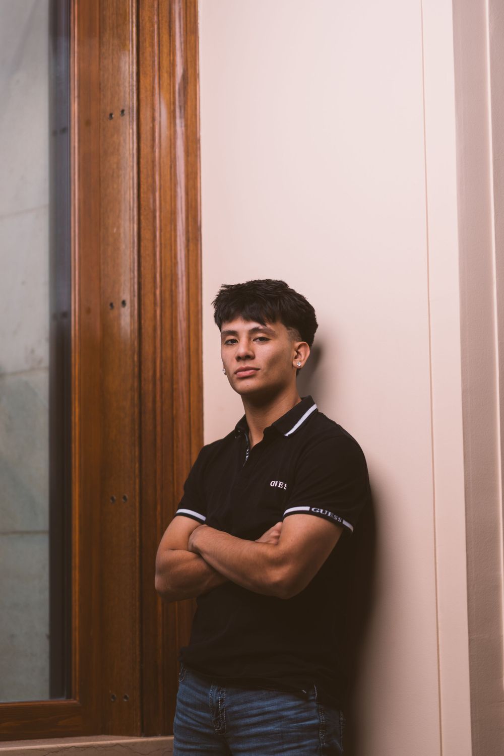 Portrait against wooden door frame in casual attire.