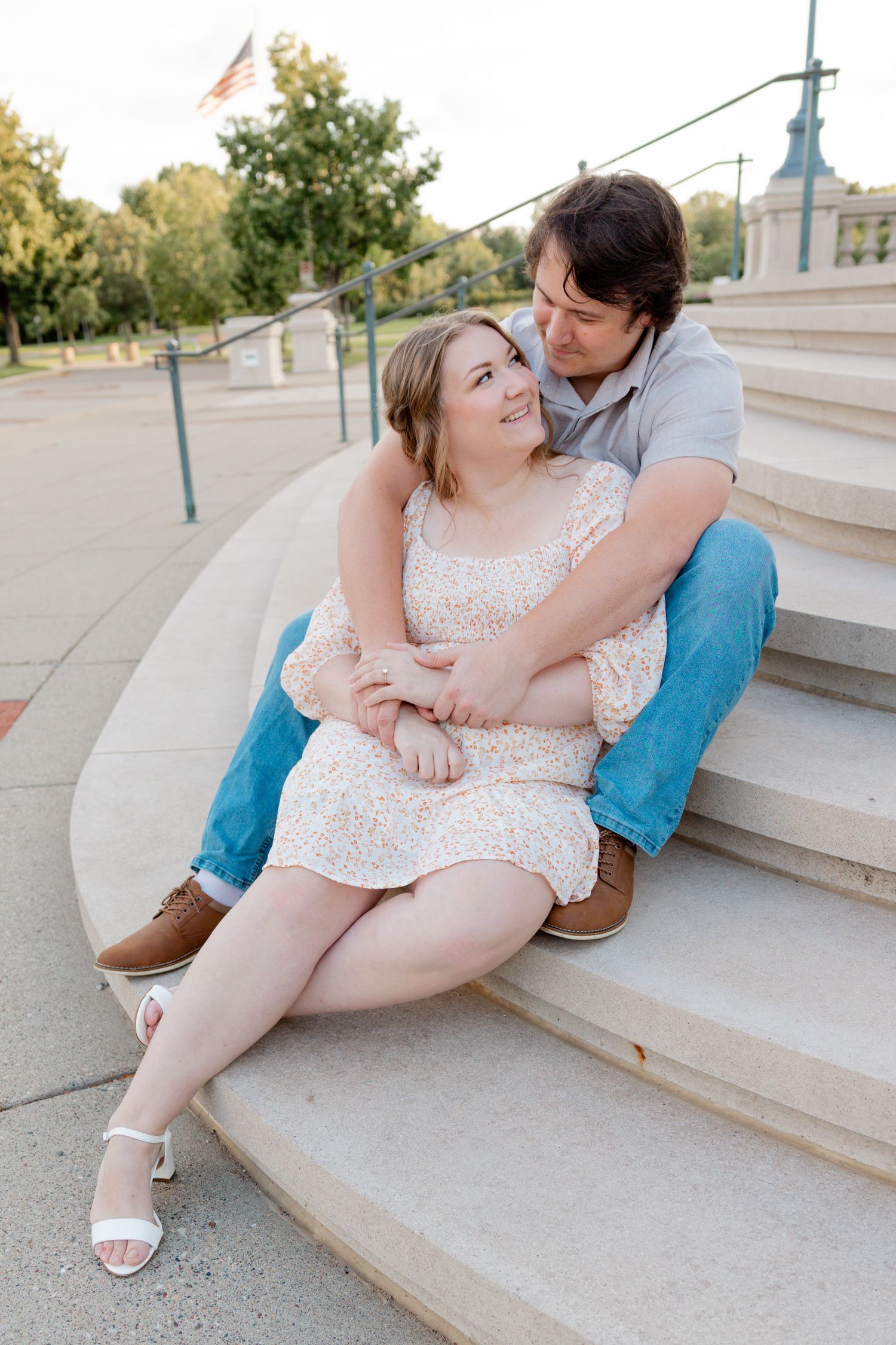 A romantic couple embraces while sitting on concrete steps outdoors.