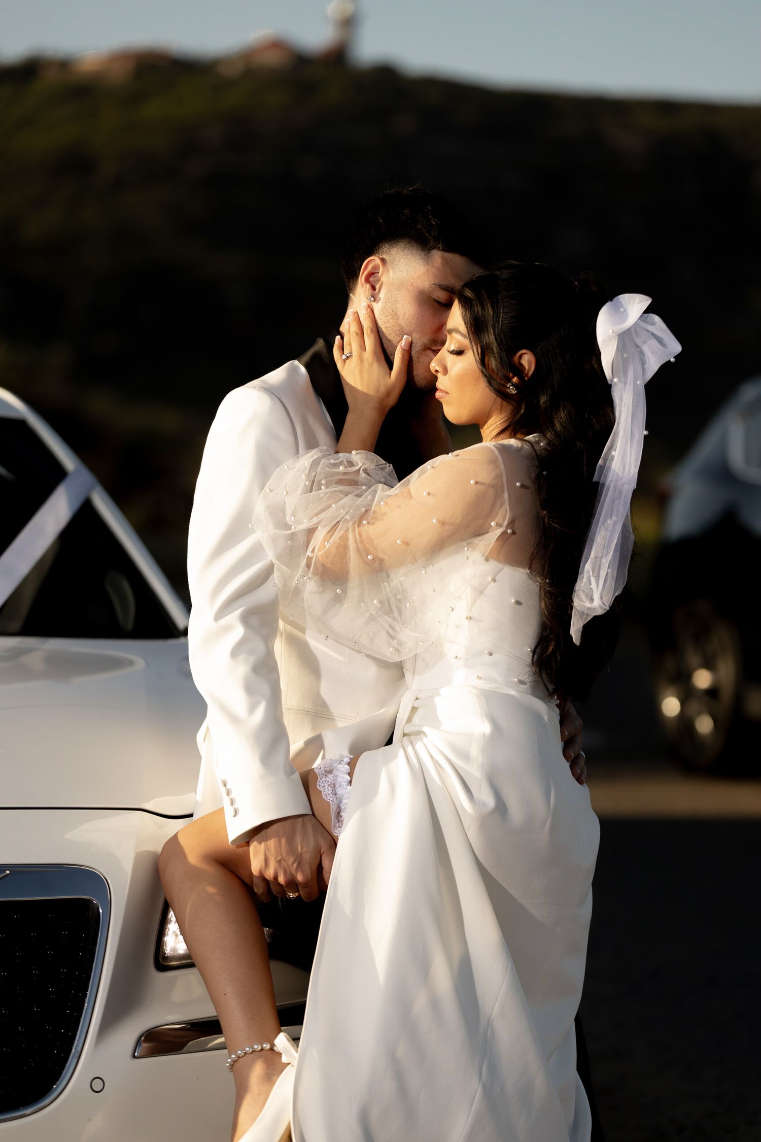 A couple in white attire sharing intimate moments in golden sunlight.