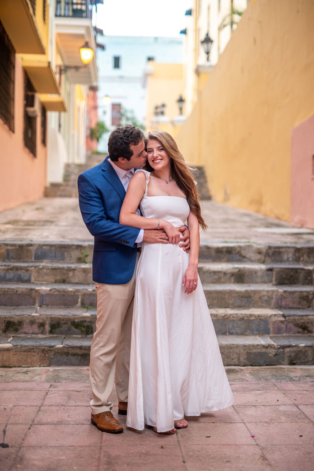 Intimate moment between couple on historic stone steps with peach colored walls.