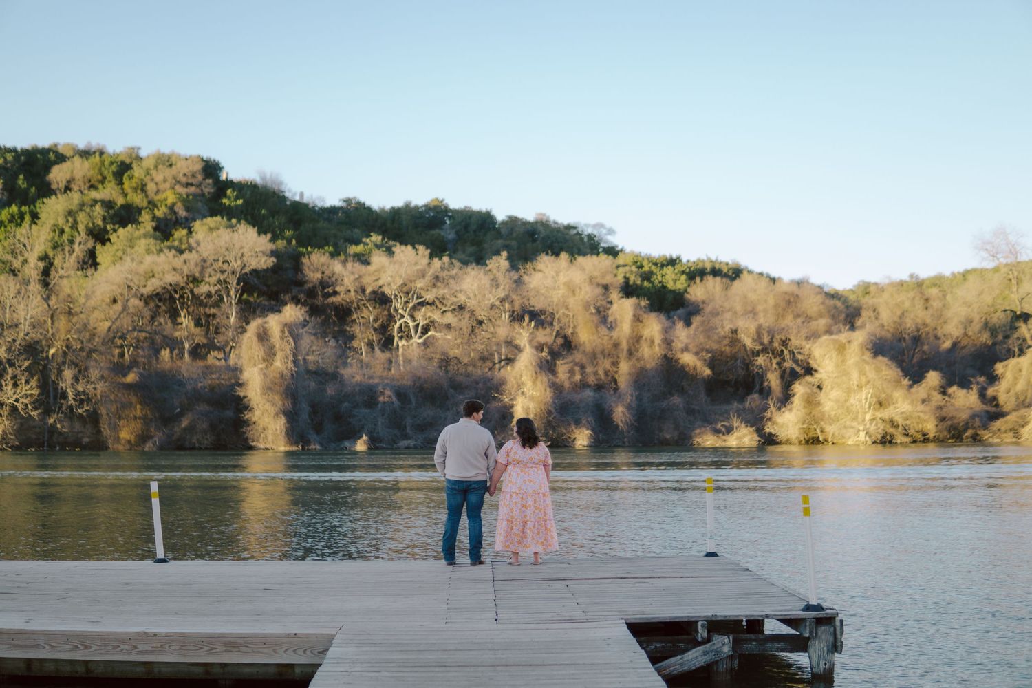 A couple stands on a wooden dock overlooking a calm lake at sat Common Fords Ranch Metropolitan Park.
