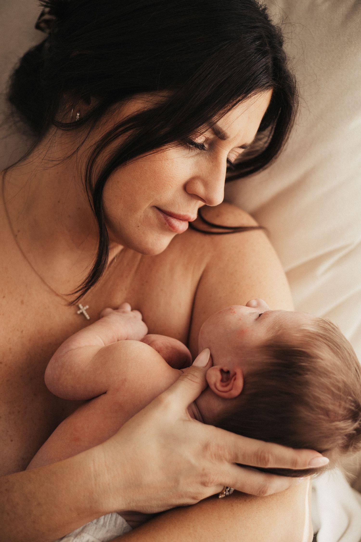 Intimate skin-to-skin bonding moment between mother and newborn in warm lighting.
