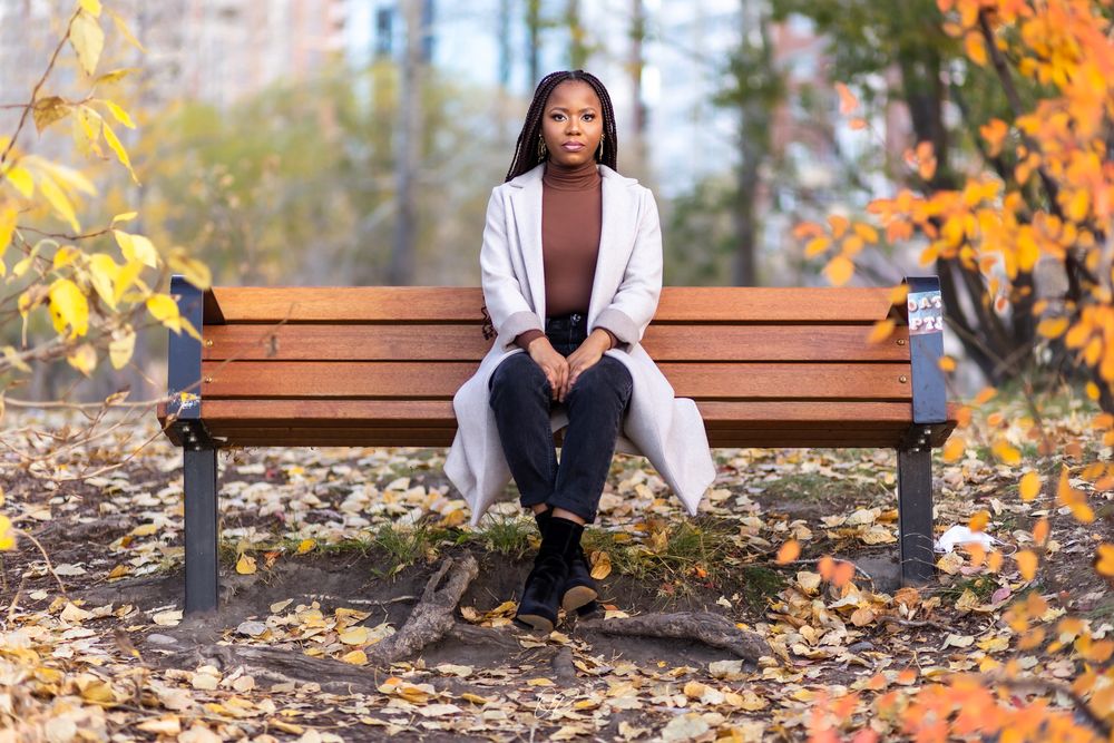 Fall outdoor portrait on wooden bench surrounded by fallen yellow leaves.