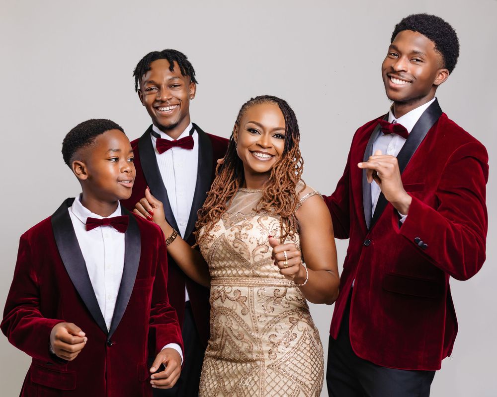Formal family portrait with matching burgundy velvet jackets and bow ties against grey background.