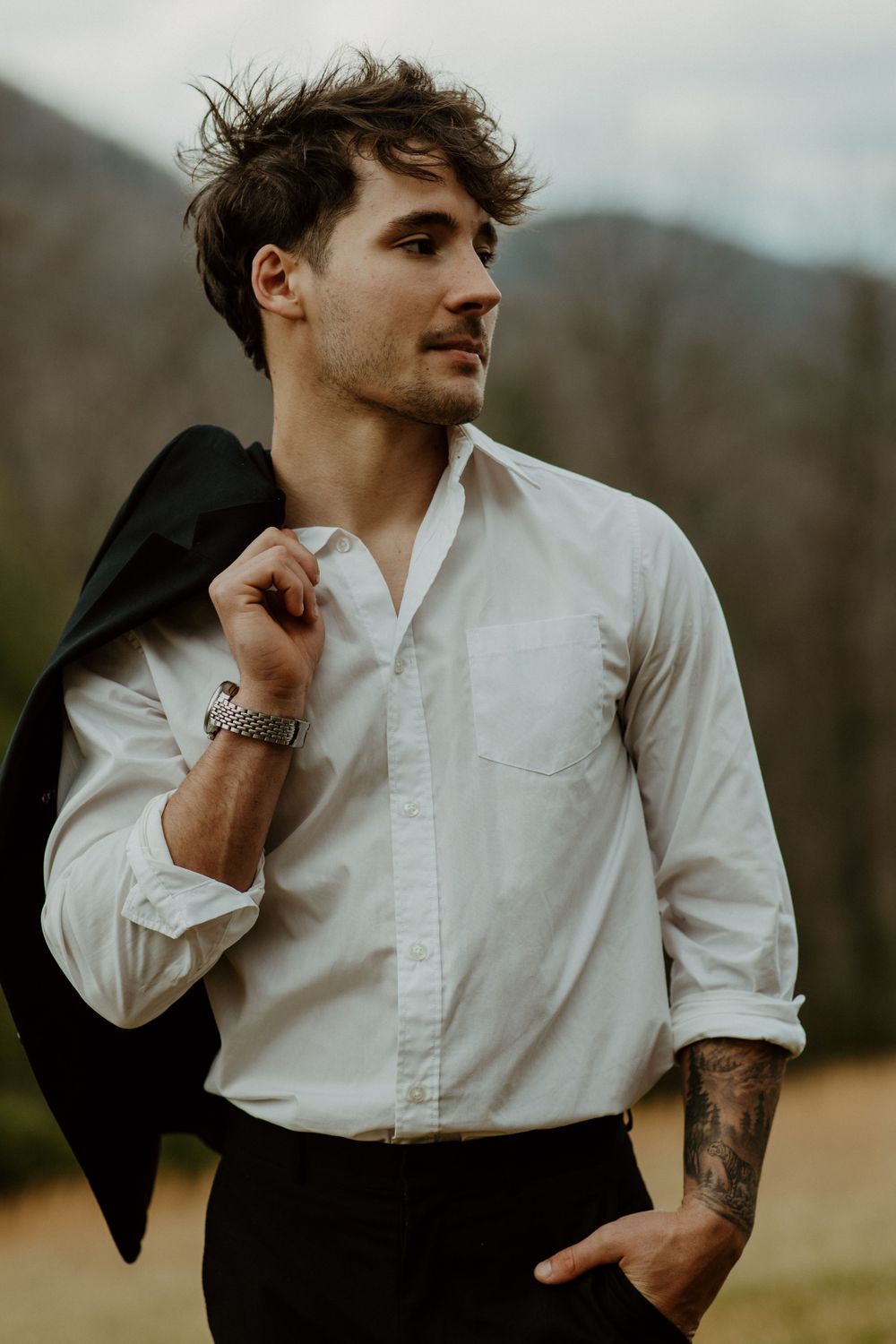 Casual portrait of groom in white button-down shirt and black pants against mountain landscape in North Georgia.