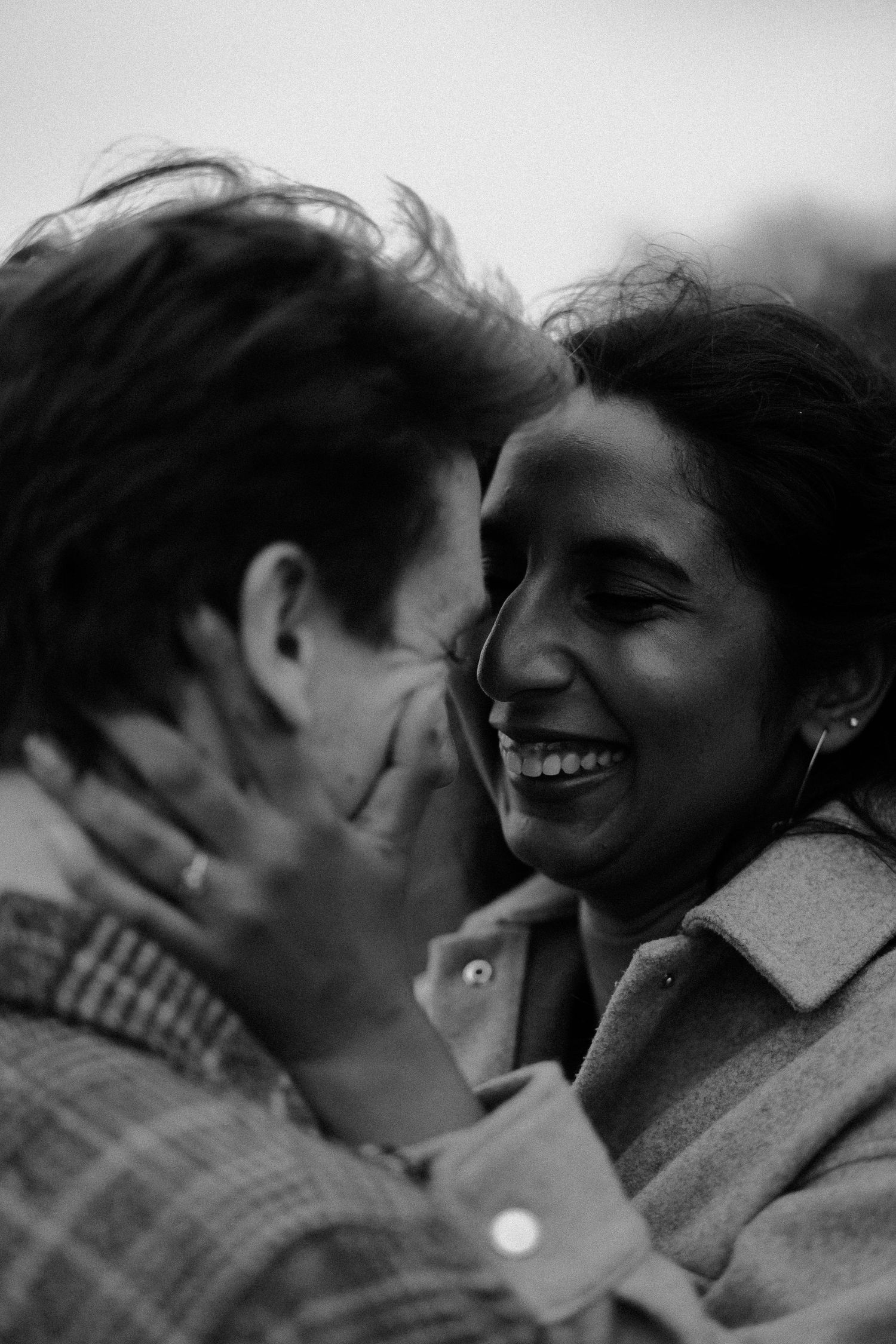 A close-up black and white photo captures an intimate laughing moment between a couple.