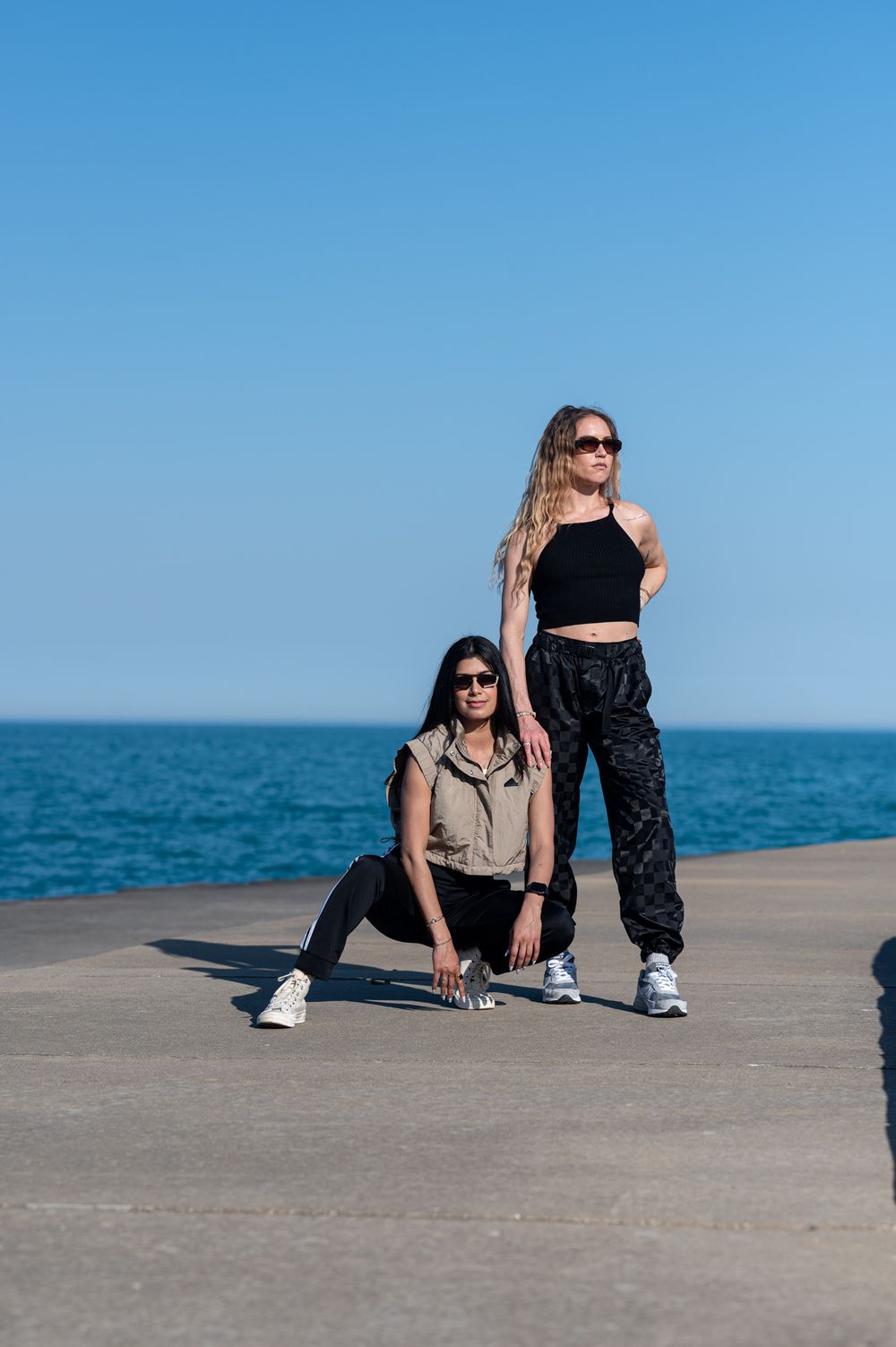 Urban fashion photoshoot with two models in casual sportswear by a body of water.