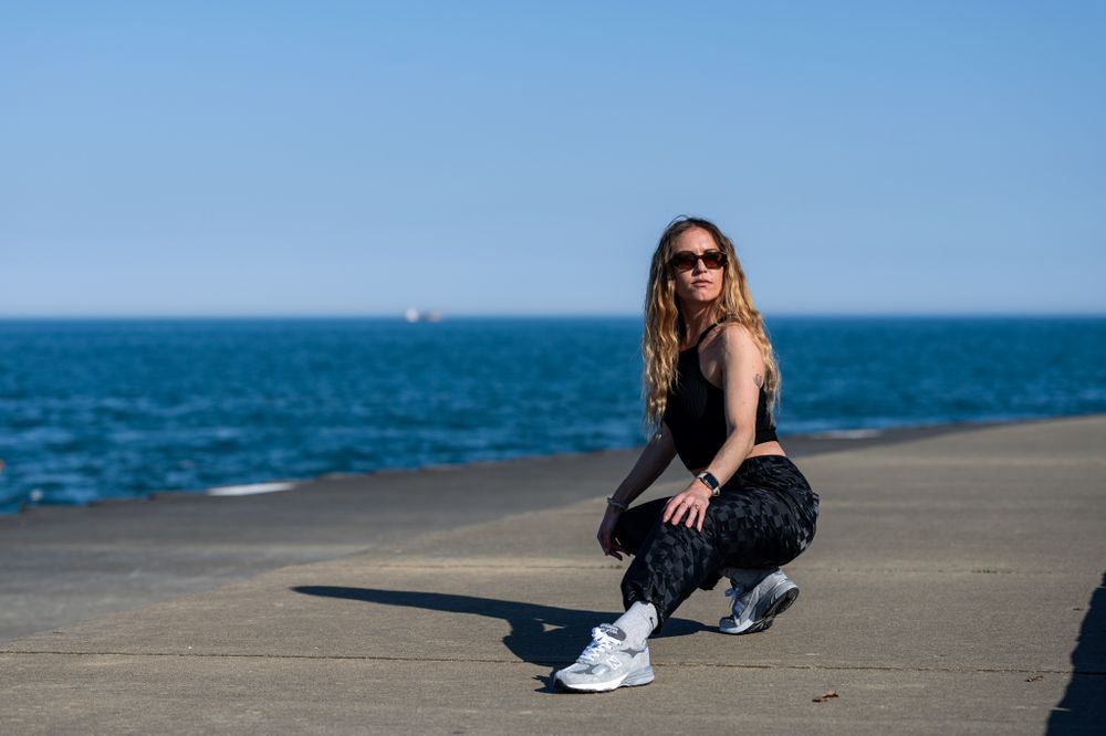 Athletic pose on concrete pier with deep blue body of water for a background.