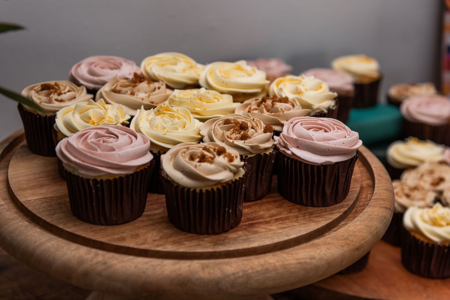 Artfully decorated cupcakes arranged on a wooden serving board.