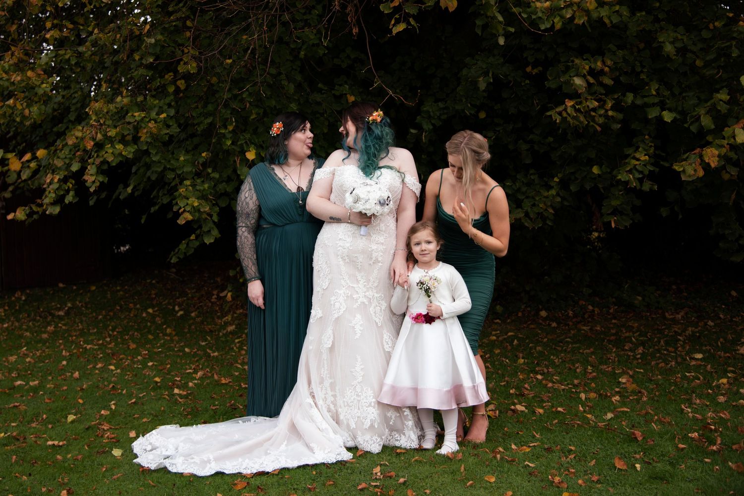 Wedding party gathered on autumn lawn with fallen leaves and formal attire.