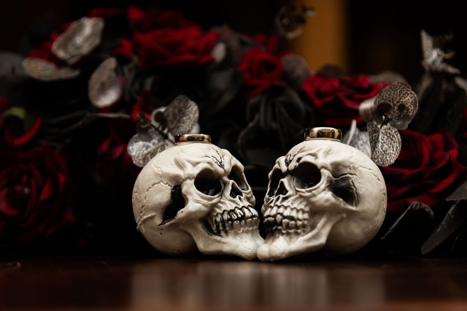 Decorative skulls arranged with dark red roses against a black background.
