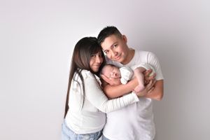 Family portrait session showing tender moments with newborn in white setting.