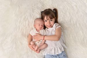 Sweet portrait of siblings cuddling together on white furry backdrop.