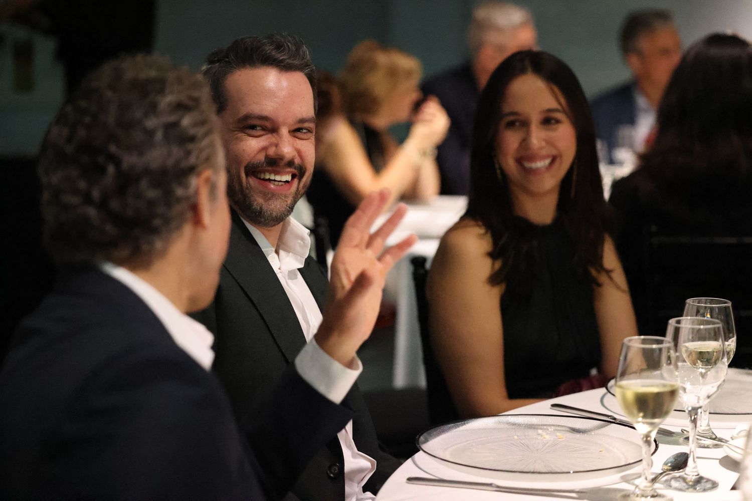 People enjoying conversation and laughter during an elegant dinner gathering at a formal event.
