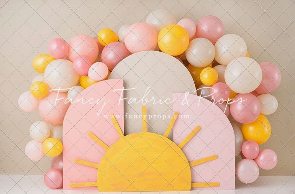 Balloon arch decoration with pink and yellow colors featuring a sun design. Cake smash theme backdrop.