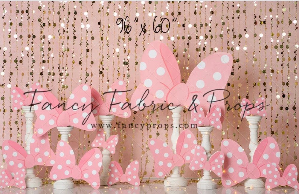 Pink and white polka dot bows arranged in front of a glittery rose gold backdrop for party decoration.