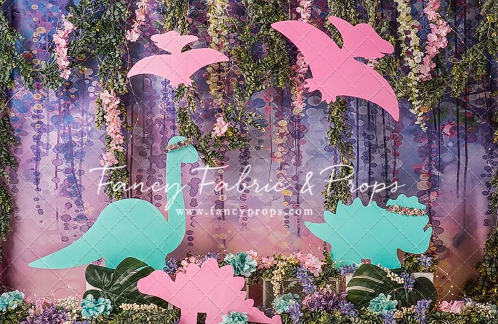 Pastel pink and mint green dinosaur silhouettes against a dreamy purple floral backdrop with hanging wisteria flowers. Cake smash session.