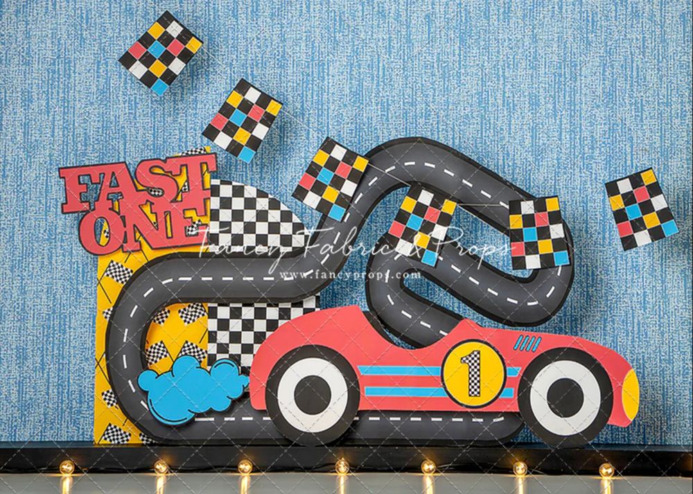 Race car themed party decor with checkered flags and a red number one racing car on a blue denim background.